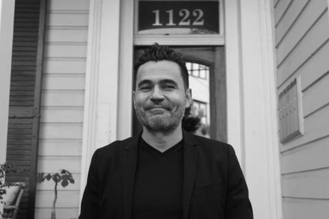 A black and white photo of Dr. Pablo Zavala. He is wearing all black and smiling.
